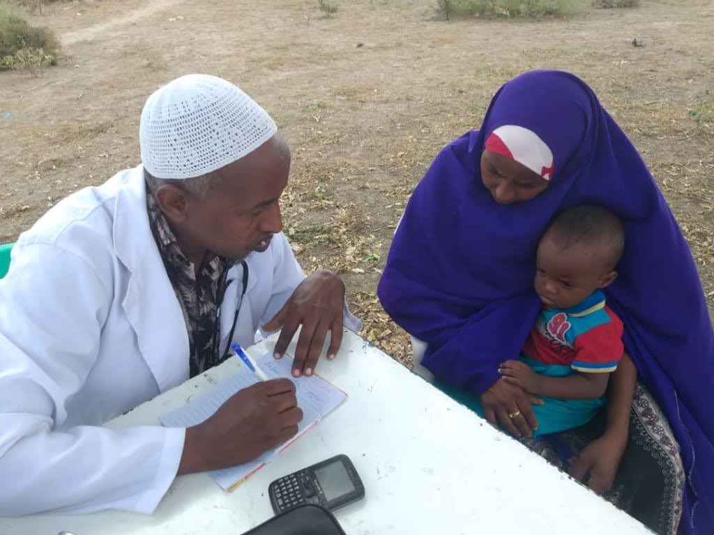  Miessairaanhoitaja neuvoo äitiä ja pientä lasta terveysasioissa.