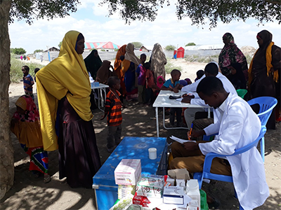 Kuva lääkäristä Somaliassa jakamssa lääkkeitä naisille ja lapsille. 
